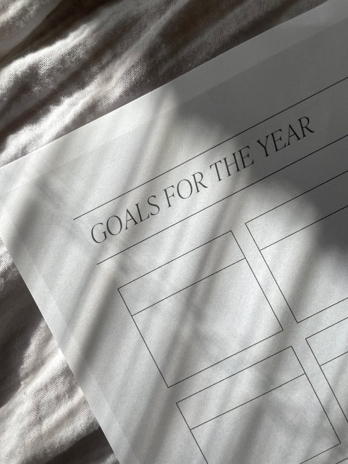 Close-up of a yearly goals planner sheet with blank spaces, captured in artistic shadow lighting.